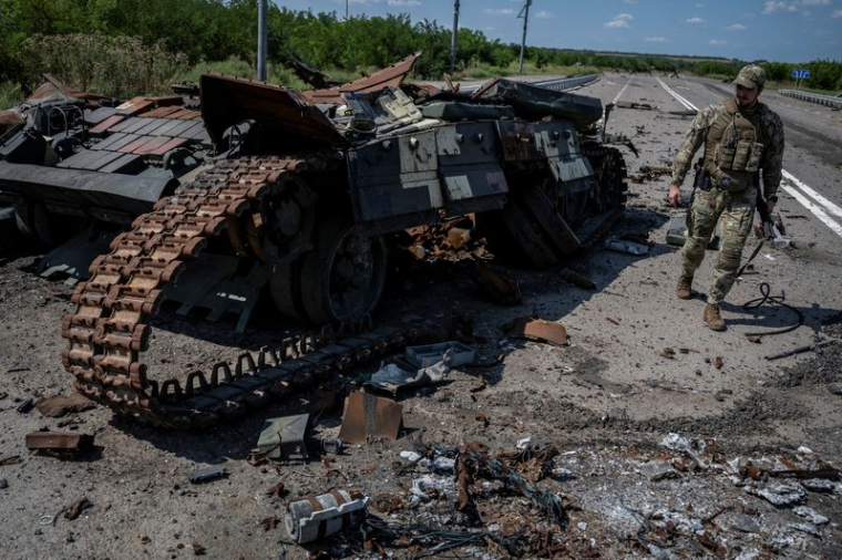 Un militaire ukrainien marche près d’un char détruit