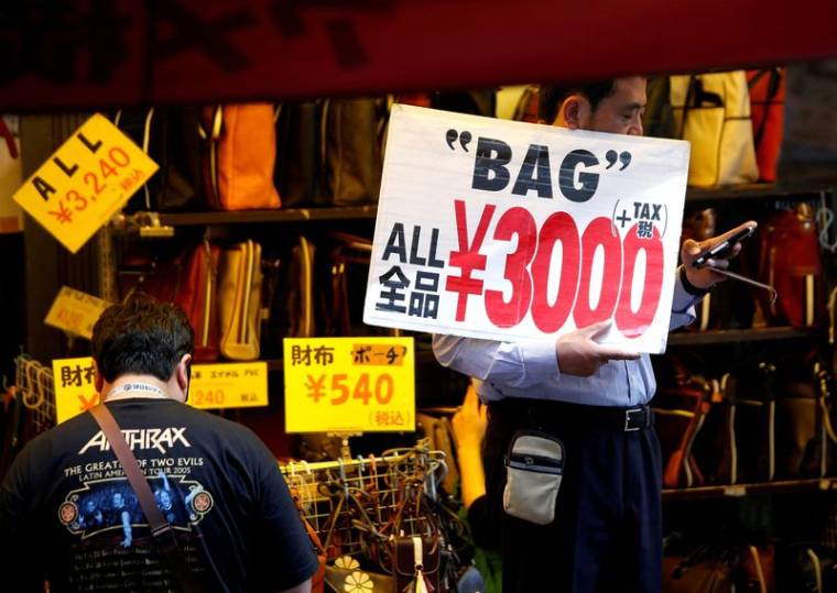 Un employé de magasin tient une pancarte pour attirer les clients à Tokyo