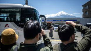 Des touristes photographient le mont Fuji avant l'installation d'un vaste filet pour cacher la vue, le 3 mai 2024 à Fujikawaguchiko, au Japon ( AFP / Philip FONG )