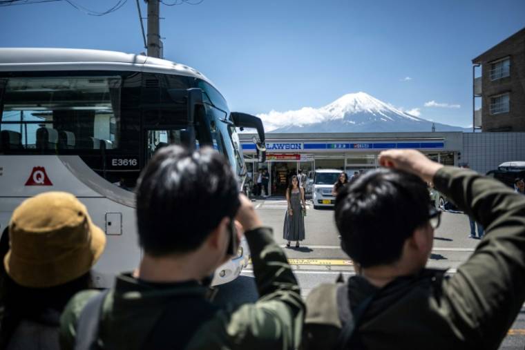 Des touristes photographient le mont Fuji avant l'installation d'un vaste filet pour cacher la vue, le 3 mai 2024 à Fujikawaguchiko, au Japon ( AFP / Philip FONG )
