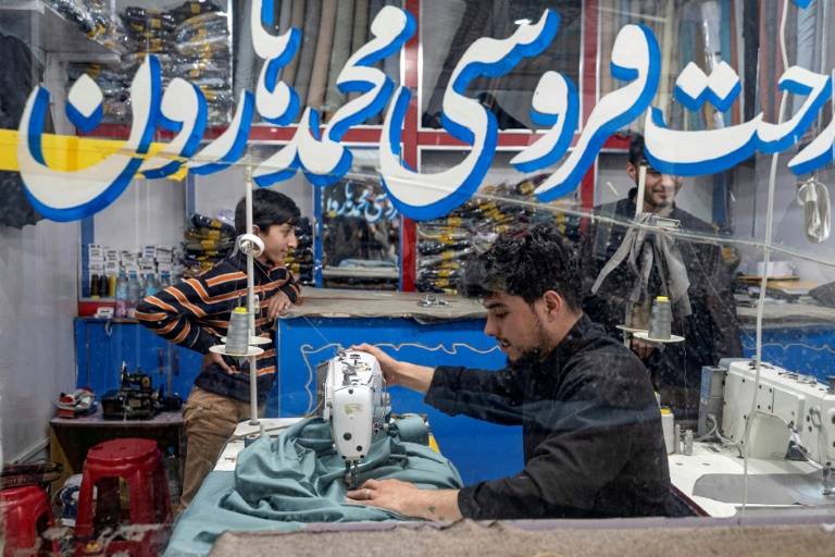 Un tailleur afghan (c) coud des vêtements avant l'Aïd al-Fitr, marquant la fin du mois de jeûne du ramadan, dans un atelier à Kaboul, le 7 avril 2024 ( AFP / Wakil KOHSAR )
