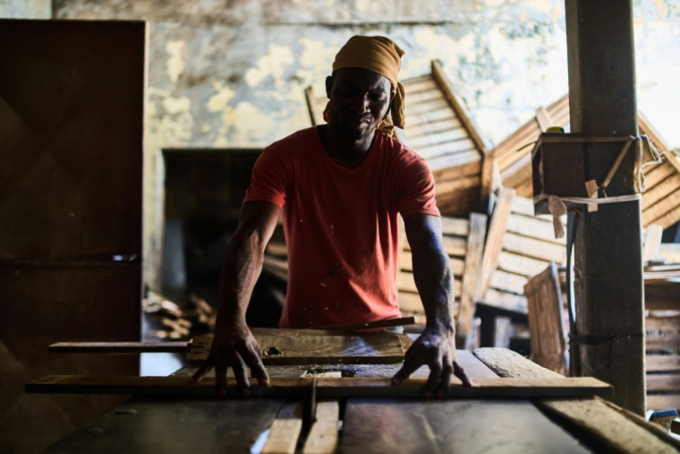 Un menuisier au travail dans l'atelier de cercueils à Beira, le 10 octobre 2024 ( AFP / Zinyange Auntony )