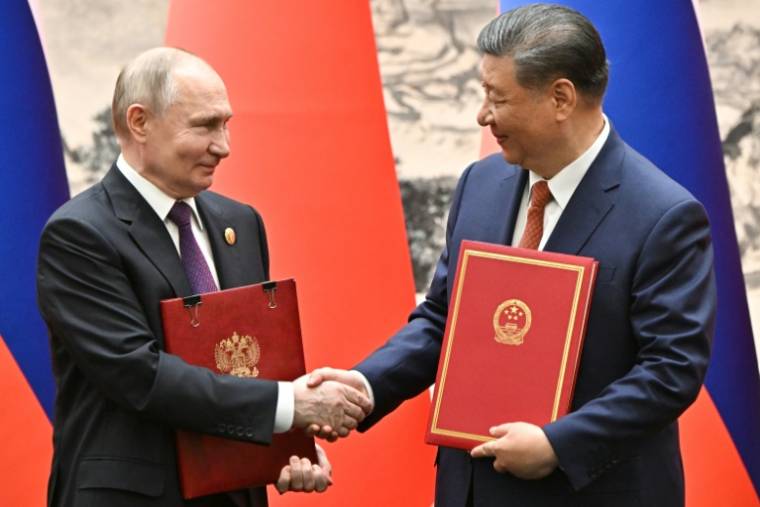 Photo diffusée par l'agence d'Etat russe Sputnik du président chinois Xi Jinping (d) et de son homologue russe Vladimir Poutine échangeant des documents à Pékin, le 16 mai 2024 ( POOL / Sergei BOBYLYOV )