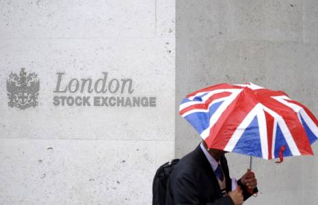 Un travailleur s'abrite de la pluie alors qu'il passe devant la Bourse de Londres