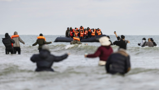 Des migrants se dirigent vers un bateau de passeurs pour tenter de traverser la Manche, sur la plage de Gravelines, près de Dunkerque (Nord) le 26 avril 2024 ( AFP / Sameer Al-DOUMY )