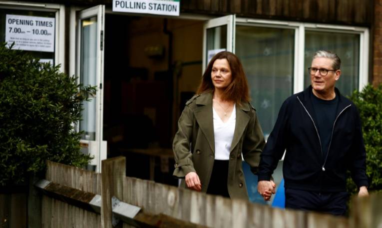 Keir Starmer, le principal chef du parti travailliste d'opposition britannique, et son épouse Victoria Starmer quittent un bureau de vote à Londres, après avoir voté pour les élections locales, le 2 mai 2024 ( AFP / BENJAMIN CREMEL )