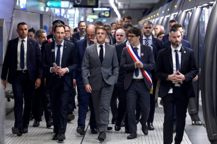 Emmanuel Macron (c) et des officiels sur le quai de la nouvelle station "Mairie de Saint-Ouen", sur la ligne 14 du métro parisien, le 24 juin 2024 ( POOL / Yves Herman )