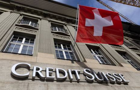 Un drapeau suisse au-dessus d'un logo du Crédit Suisse à Berne, en Suisse