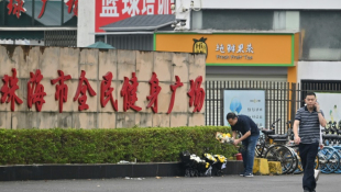 Des employés enlèvent des fleurs d'un lieu d'hommage improvisé devant le centre sportif de Zhuhai, deux jours après une attaque meurtrière à la voiture-bélier, le 13 novembre 2024 dans la province du Guangdong, dans le sud de la Chine ( AFP / HECTOR RETAMAL )