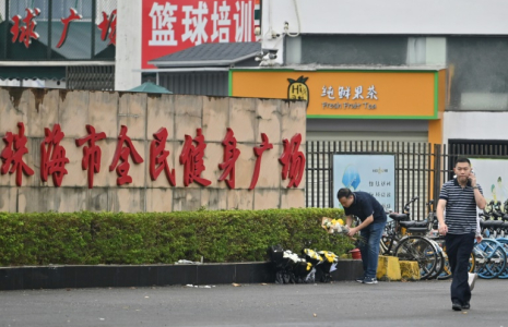 Des employés enlèvent des fleurs d'un lieu d'hommage improvisé devant le centre sportif de Zhuhai, deux jours après une attaque meurtrière à la voiture-bélier, le 13 novembre 2024 dans la province du Guangdong, dans le sud de la Chine ( AFP / HECTOR RETAMAL )