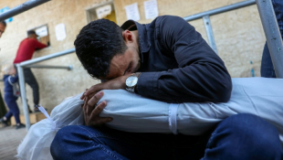 Un homme pleure en tenant le corps d'un enfant tué lors d'une frappe sur le camp de réfugiés de Nousseirat, à l'hôpital des Martyrs d'al-Aqsa à Deir el-Balah, le 21 novembre 2022 ( AFP / Bashar TALEB )