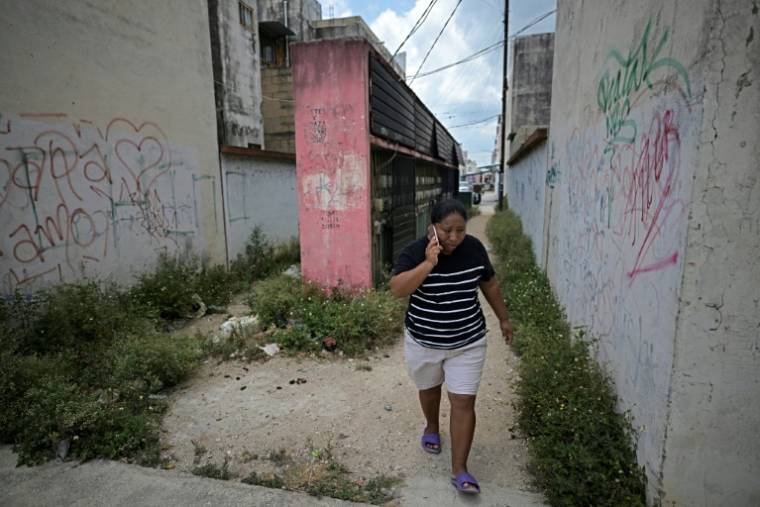 Rosalina Gomez, femme de ménage à l'aéroport de Cancun, parle au téléphone près de chez elle dans une zone périphérique de la station balnéaire mexicaine le 23 avril 2024. ( AFP / CARL DE SOUZA )