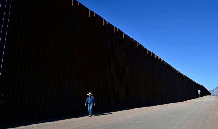 L'éleveur John Ladd marche le long du mur frontalier entre les Etats-Unis et le Mexique, le 17 avril 2024 près de Palominas,en Arizona ( AFP / Frederic J. BROWN )