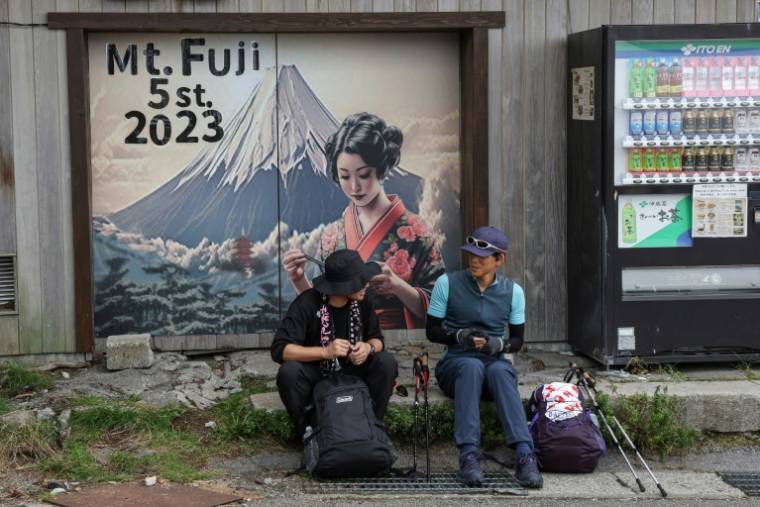 Deux randonneurs se reposent au pied du sentier du mont Fuji, la plus haute montagne japonaise culminant à 3.776 mètres, le 31 août 2023 ( AFP / Mathias CENA )