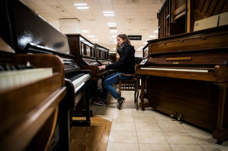 Une bénévole essaie un vieux pianos dans l'atelier de "Pianodrome", le 9 février 2023 à Edimbourg, en Ecosse ( AFP / Andy Buchanan )