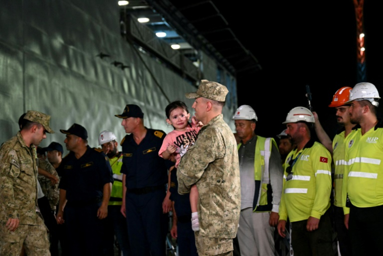 Un soldat tient dans ses bras un enfant évacué alors que des citoyens turcs évacués du Liban débarquent du navire de guerre turc TCG L402 Bayreaktar après son arrivée au port de Mersin, dans le sud de la Turquie, le 10 octobre 2024 ( AFP / OZAN KOSE )