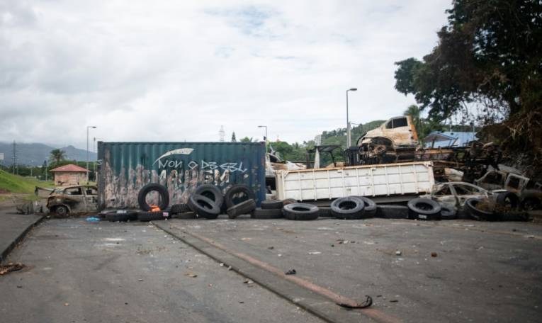 Des voitures brûlées et des pneus sur un barrage à l'entrée du quartier de Montravel à Nouméa, le 21 mai 2024 ( AFP / Delphine Mayeur )