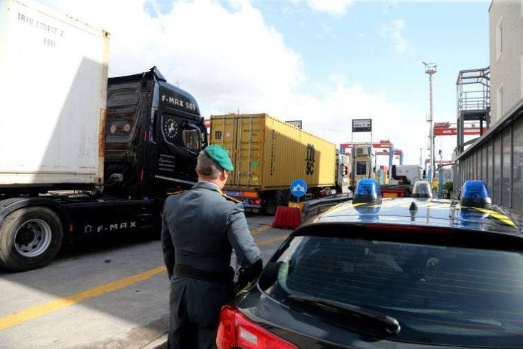 Un officier de la Guardia di Finanza, la police italienne chargée de la criminalité financière et de la contrebande, observent des camions dans la zone commerciale du port de Naples, le 29 février 2024 ( AFP / CARLO HERMANN )