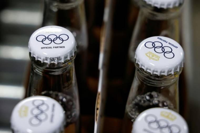 Le logo des Jeux olympiques sur des capsules de bouteilles de bière sans alcool Corona Cero, sur une ligne de production à la brasserie Anheuser-Busch InBev (AB InBEV), le 23 avril 2024 à Louvain, en Belgique ( AFP / Kenzo TRIBOUILLARD )
