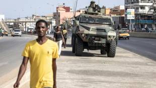 Des passants marchent à côté d'un blindé de l'armée à Dakar, le 2 juin 2023 ( AFP / JOHN WESSELS )