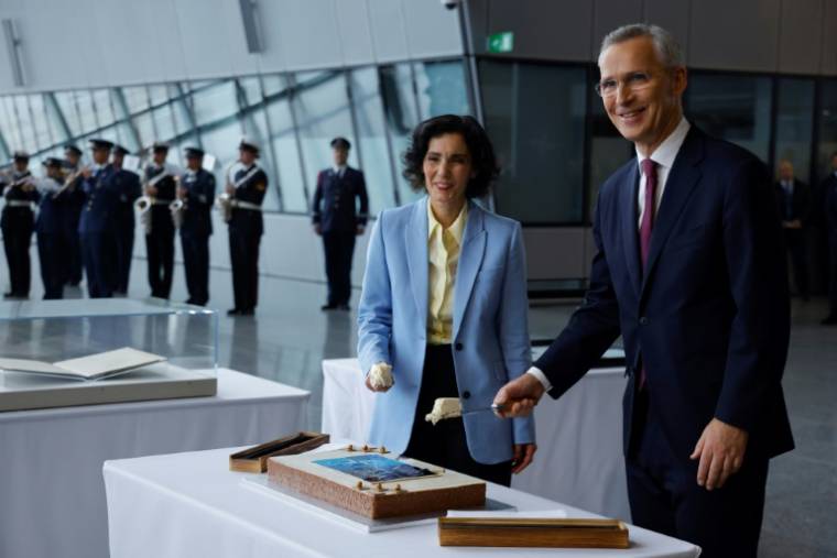 La ministre belge des Affaires étrangères Hadja Lahbib et le secrétaire général de l'Otan Jens Stoltenberg partagent un gâteau pour marquer les 75 ans de l'Alliance, le 4 avril 2024 à Bruxelles  ( AFP / Kenzo TRIBOUILLARD )