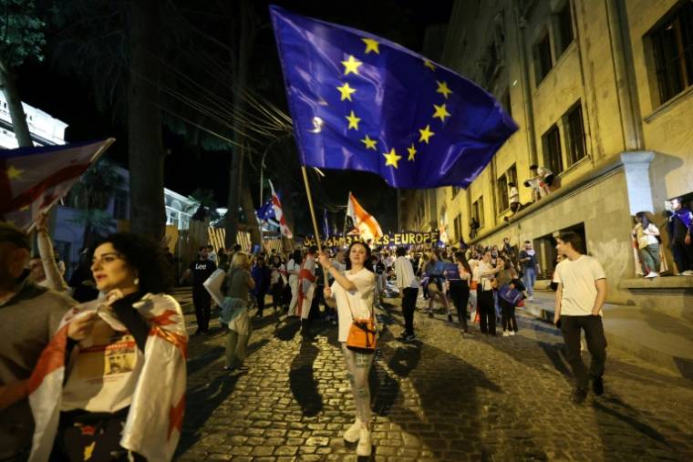 Une manifestante brandit un drapeau européen pendant une manifestation contre le projet de loi sur "l'influence étrangère", le 28 avril 2024 à Tbilissi ( AFP / Giorgi ARJEVANIDZE )