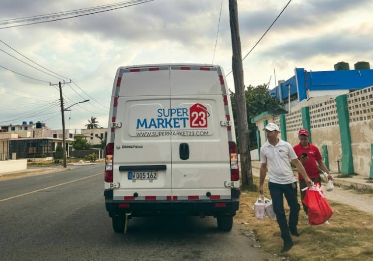 Des employés d'une société américaine de livraison transportent des colis de nourriture dans un quartier de La Havane, le 22 mai 2024 à Cuba ( AFP / YAMIL LAGE )