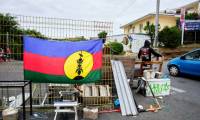 Un drapeau kanak sur un barrage dans le quartier de Magenta, à Nouméa, où un manifestant régule la circulation, le 22 mai 2024 en Nouvelle-Calédonie ( AFP / Theo Rouby )