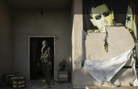 Un combattant rebelle passe devant un portrait abîmé du président syrien déchu Bachar al-Assad dans une base militaire de la capitale Damas, le 26 décembre 2024 ( AFP / Sameer Al-DOUMY )