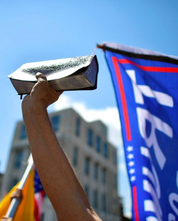 Un homme brandit une bible et un drapeau Trump  devant le capitole de la  Pennsylvanie le 15 mai 2020  ( GETTY IMAGES NORTH AMERICA / Mark Makela )