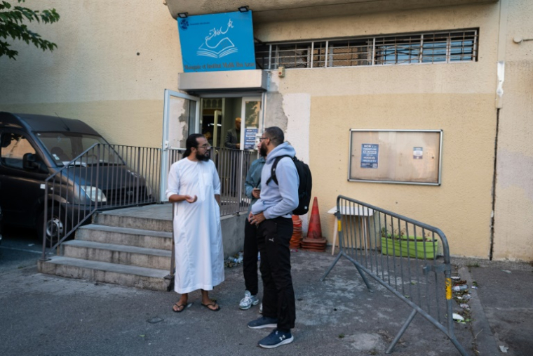 L'imam Ismail (g) de la mosquée des Bleuets parle avec des habitants du quartier après sa conférence de presse, le 9 septembre 2024 à Marseille ( AFP / MIGUEL MEDINA )