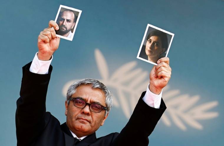 Le réalisateur iranien Mohammad Rasoulof brandit les photos de l'acteur iranien Missagh Zareh, à gauche, et de l'actrice iranienne Soheila Golestani, à droite, le 24 mai 2024, au festival de Cannes, dans les Alpes-Maritimes ( AFP / Sameer Al-Doumy )
