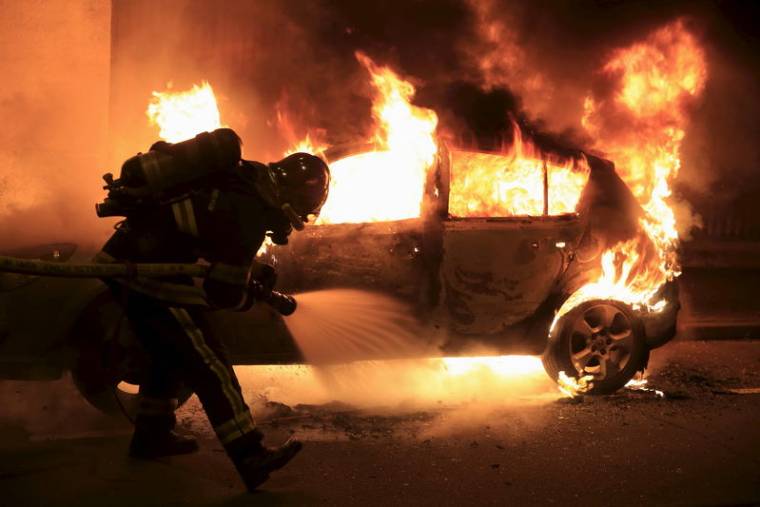 Firefighters extinguish a burning car during New Year celebrations in Lille, northern France