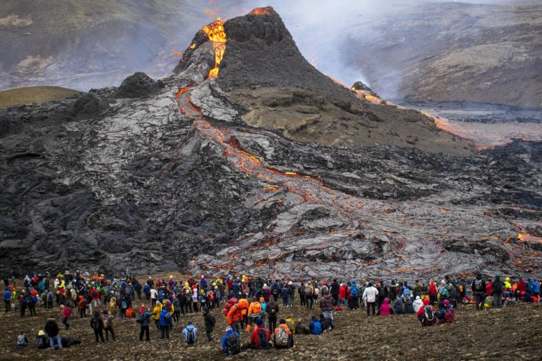 Des randonneurs regardent la lave qui s'écoule du volcan en éruption Fagradalsfjall, à quelque 40 km à l'ouest de la capitale islandaise Reykjavik, le 21 mars 2021. ( AFP / JEREMIE RICHARD )