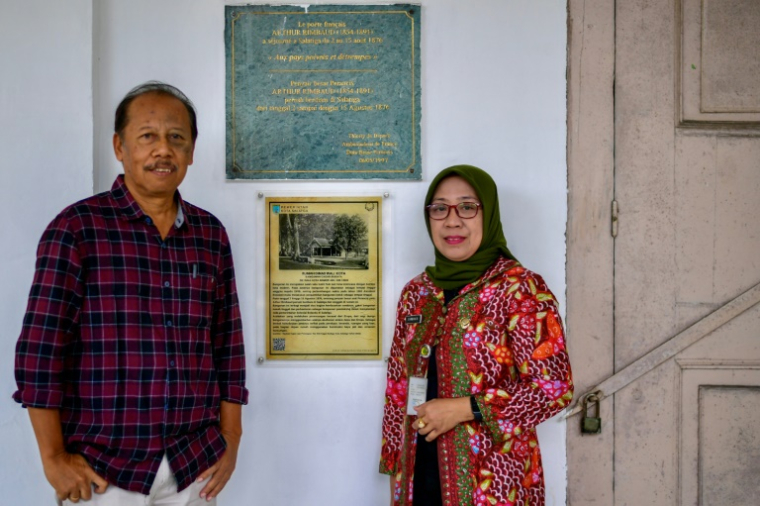 L'historien Eddy Supangkat (à gauche) et Sri Sarwanti, directrice des Archives de Salatiga, devant une plaque portant le nom du poète français Arthur Rimbaud dans la résidence du maire de Salatiga, au centre de Java, le 25 septembre 2024 ( AFP / BAY ISMOYO )