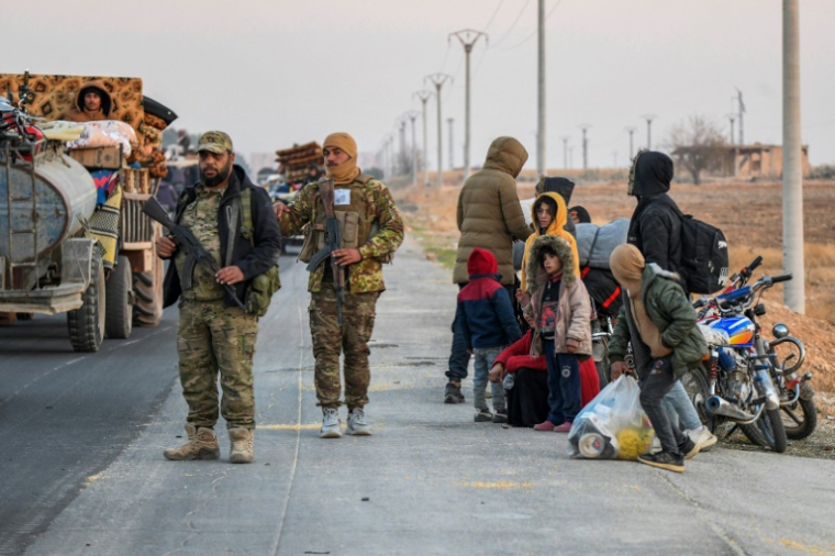 Des combattants anti-régime sur le bord d'une route alors que des Kurdes syriens déplacés fuient les zones auparavant contrôlées par les Forces démocratiques syriennes (FDS) dirigées par les Kurdes, et prises par les rebelles islamistes, le 2 décembre 2024 dans la province d'Alep ( AFP / Rami al SAYED )