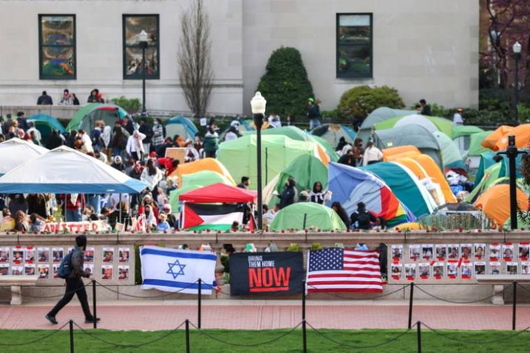 Un homme passe devant des portraits d'otages israéliens et en arrière-plan le "campement de solidarité avec Gaza" à l'université Columbia à New York, le 23 avril 2024 ( AFP / Charly TRIBALLEAU )