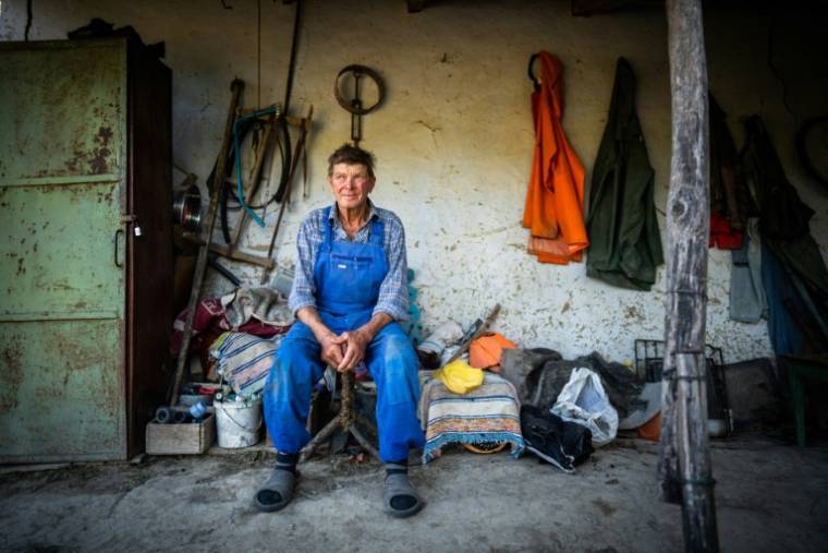 Ion Giuvanovici assis devant sa maison à Plauru, à 300 km à l'est de Bucarest, le 11 septembre 2023 en Roumanie ( AFP / MIHAI BARBU )