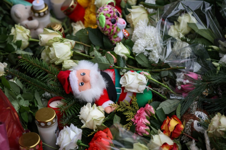 Une figurine de père Noël parmi les fleurs et bougies déposées près du lieu de l'attaque à la voiture-bélier contre un marché de Noël à Magdebuurg, dans l'est de l'Allemagne, le 21 décembre 2024 ( AFP / Ronny HARTMANN )