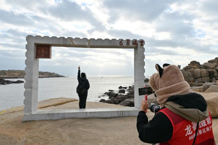 Un touriste pose pour une photo sur l'île pittoresque de Pingtan, territoire chinois le plus proche de l'île principale de Taïwan, le 10 décembre 2024 ( AFP / ADEK BERRY )