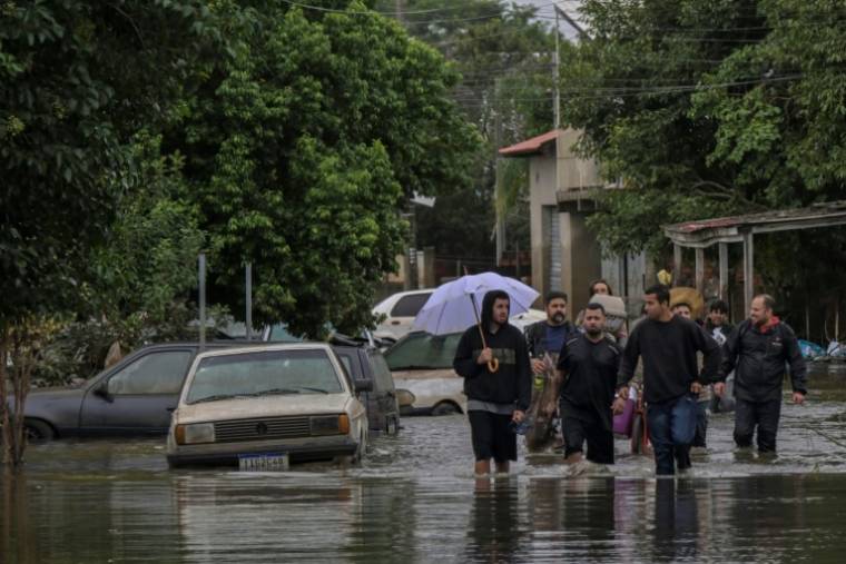 Des habitants se déplacent dans une rue inondée de la ville de Canoas, dans le sud du Brésil, le 13 mai 2024 ( AFP / NELSON ALMEIDA )