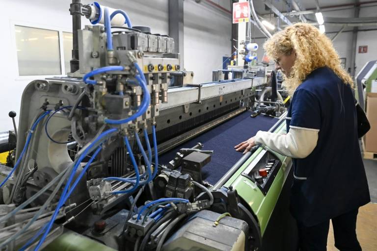 Une technicienne contrôle une machine à textile dans l'usine de la marque 1083 à Rupt-sur-Moselle, dans les Vosges, le 12 mars 2024 ( AFP / Jean-Christophe  VERHAEGEN )