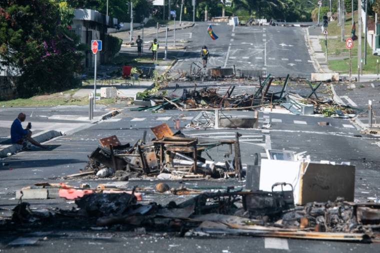 Une rue bloquée par des objets incendiés et des débris, dans le quartier Magenta à Nouméa en Nouvelle-Calédonie, le 18 mai 2024 ( AFP / Delphine Mayeur )