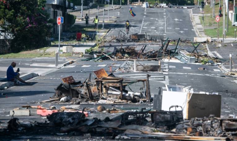 Une rue de Nouméa, en Nouvelle-Calédonie, bloquée par des débris, le 18 mai 2024  ( AFP / Delphine Mayeur )
