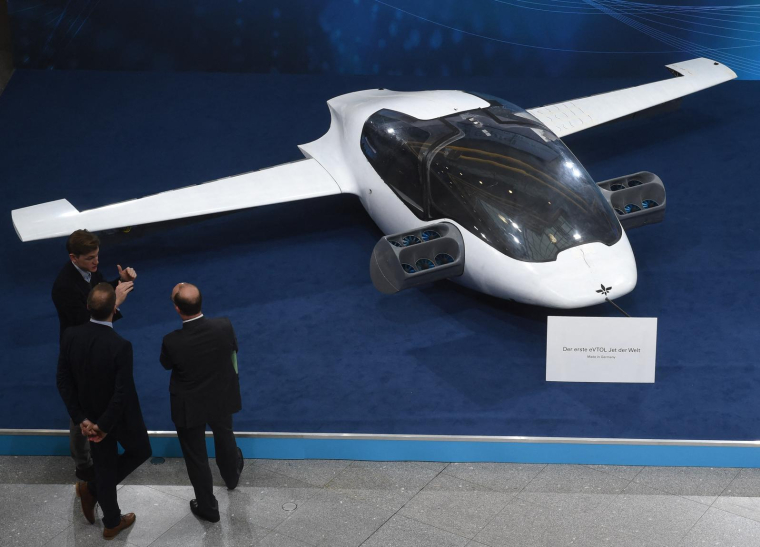 Des visiteurs regardent un prototype du premier taxi volant, l'eVTOL - jet électrique à décollage et atterrissage vertical - de la société Lilium. Salon Digital Summit (Digital Gipfel) à Nuremberg (sud de l'Allemagne), le 4 décembre 2018. ( AFP / CHRISTOF STACHE )