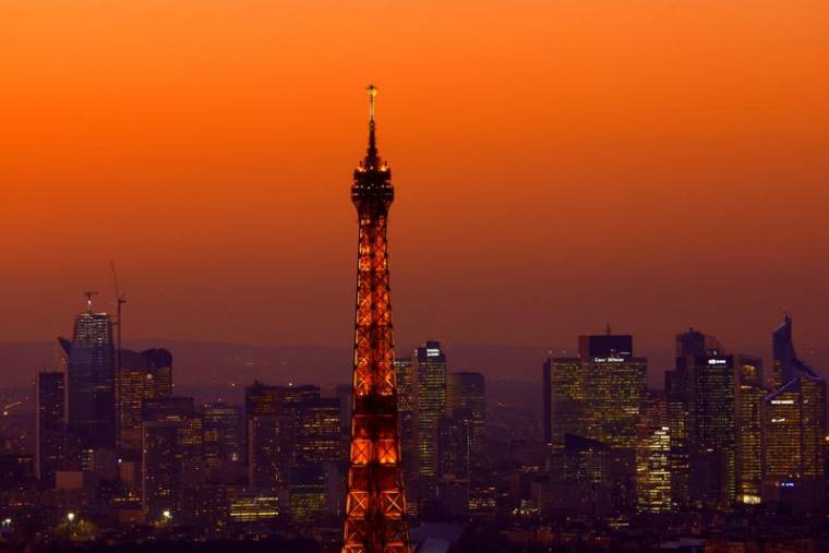 Photo d'archives de la Tour Eiffel au coucher du soleil avec le quartier de La Défense en arrière-plan