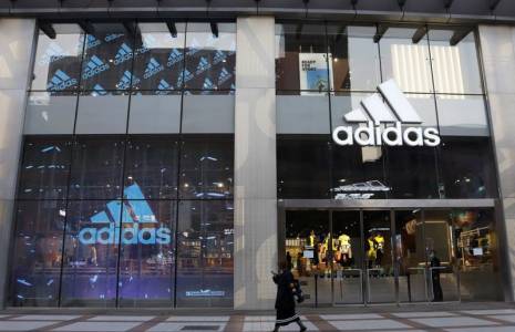 Une femme passe devant un magasin d'Adidas dans un centre commercial de Pékin