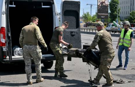 Des policiers spécialisés ukrainiens chargent des débris de missiles russes dans une voiture  le 29 mais 2023 à Kiev ( AFP / Sergei SUPINSKY )