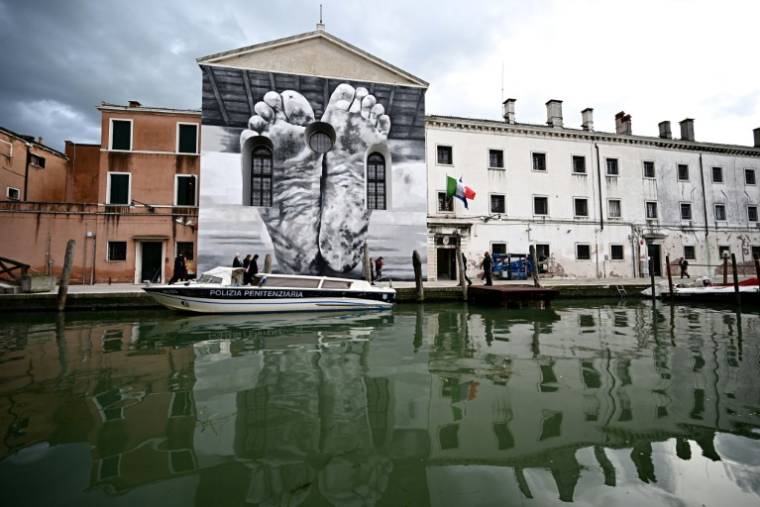 Une fresque murale de l'artiste Maurizio Cattelan sur la façade de la prison pour femmes de la Giudecca, abritant le pavillon du Vatican, lors de la pré-ouverture de la 60e exposition d'art de la Biennale de Venise, le 18 avril 2024 ( AFP / GABRIEL BOUYS )