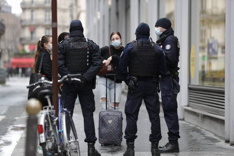Des policiers intimant l'ordre à des passantes de porter un masque dans les rues de Paris, le 31 janvier 2021. ( AFP / GEOFFROY VAN DER HASSELT )